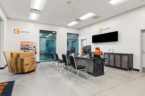 A storage facility leasing office featuring a customer service desk, chairs, and moving supplies for sale