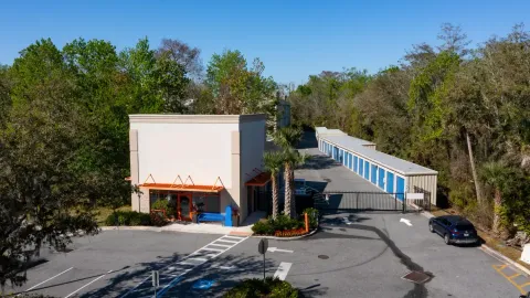 Aerial view of a storage rental office and gated drive-up units with blue roll-up doors