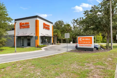 Exterior of a Mini Mall Storage facility with orange signage, glass storefront, and paved entrance drive