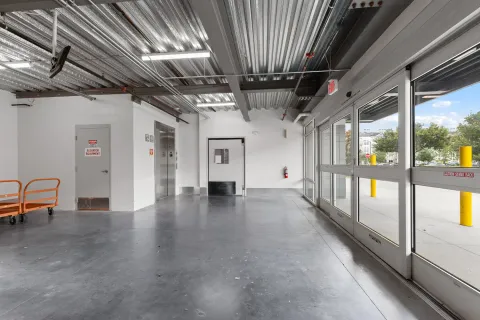 Indoor loading area featuring glass sliding doors, an elevator, and a corrugated metal ceiling