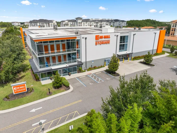 Aerial view of a white multi-story Mini Mall Storage building with glass windows and orange unit doors