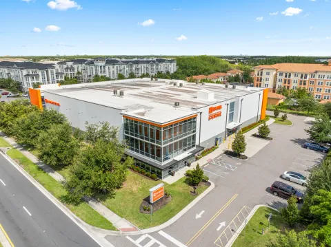 Aerial view of a multi-story Mini Mall Storage facility with a glass corner office and paved parking lot