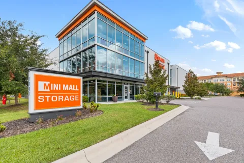 Exterior of a Mini Mall Storage facility featuring a multi-story glass office and large orange signage