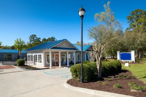 A storage rental office building with a blue metal roof, orange door, and lamp post
