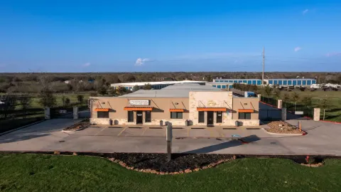 Main office building with orange awnings and a paved parking lot in front of storage units