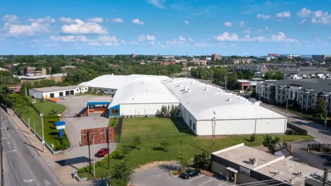 Aerial view of a white multi-story storage building with arched roofs and a gated entrance lot