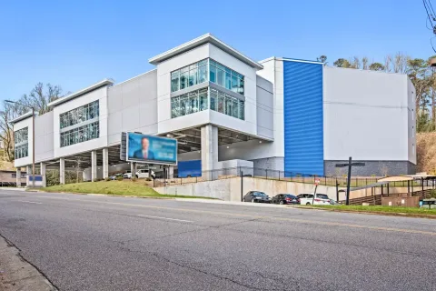 Exterior view of a multi-story white and blue storage facility with large windows and a parking area