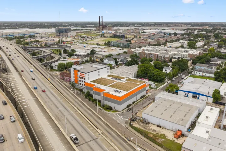 Aerial view of a multi-story self-storage facility with orange accents located next to a major highway turnoff
