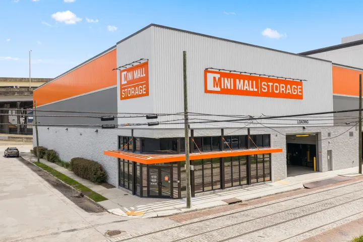 Exterior view of a multi-story Mini Mall Storage facility featuring an orange awning and loading bay