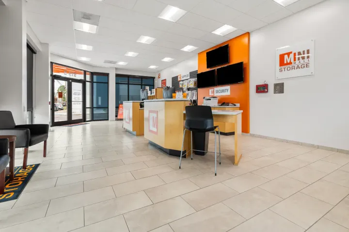 A bright rental office for Mini Mall Storage featuring customer service counters, retail supplies, and monitors