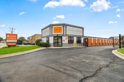 A single story self storage office with glass doors next to a row of orange drive-up units