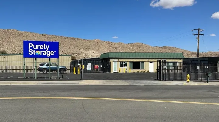 Purely Storage facility office and gated entrance with a blue sign and desert mountains in the background
