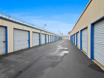 Long row of drive-up storage units with security fencing at a facility.