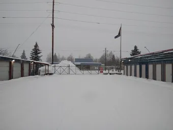 Storage facility driveway in winter with snow, buildings, and gate