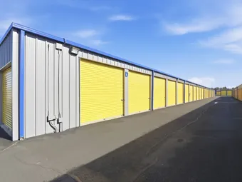 Long row of drive-up storage units with yellow doors.