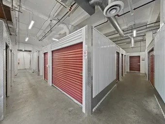 Main aisle of indoor storage units with red roll-up doors.