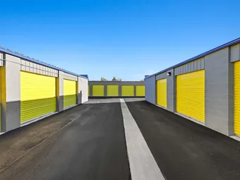Outdoor drive-up storage units with bright yellow doors.