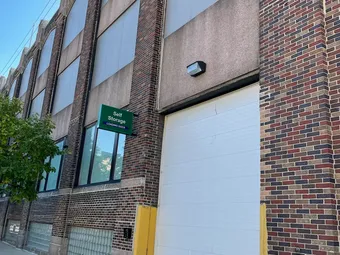 Exterior view showing a loading dock roll-up door and a storage sign