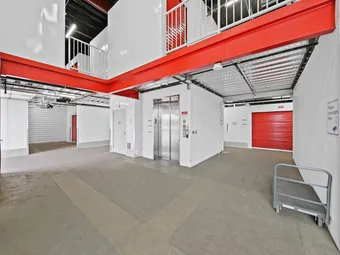 Interior hallway with security cameras, elevator, and red unit doors