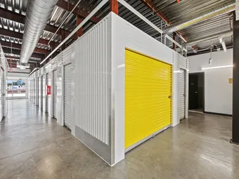 Indoor hallway with various storage unit doors, one yellow.