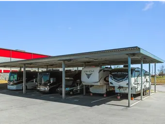 Covered RV storage in North Augusta on Cork Tree Bend, featuring motorhomes and fifth-wheel campers parked under a metal canopy in an outdoor paved lot