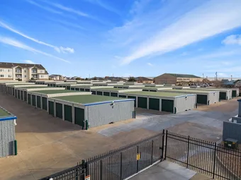Aerial view of multiple rows of drive-up storage units and security fence.