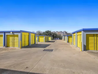 Storage unit drive-up with rows of yellow storage doors.