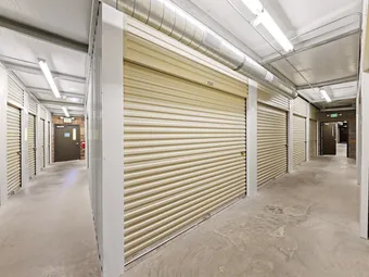 Indoor climate-controlled storage unit hallway with tan rollup doors.