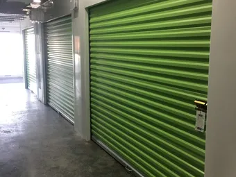 Indoor storage hallway with green roll-up unit doors.