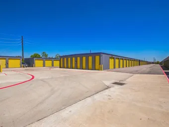 Rows of yellow storage unit doors visible from a wide paved driveway.