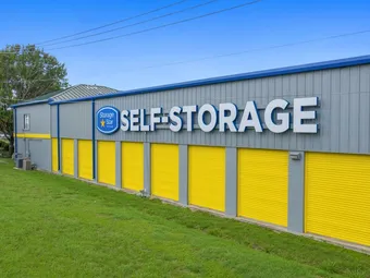 Exterior of storage building with yellow doors and blue signage.