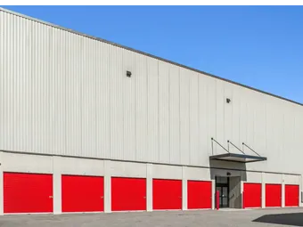 Large multi-story storage building with tan corrugated siding and a row of red drive-up storage units in Aiken on Hamilton Dr