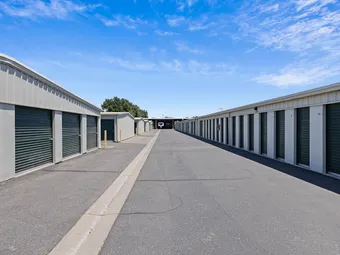 Long rows of outdoor storage units with green roll-up doors.