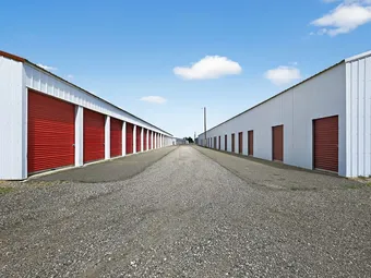 Exterior view of two rows of self storage units with red doors.
