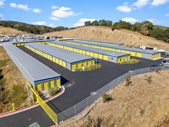 Paved driveways and storage units with yellow doors on a sunny day