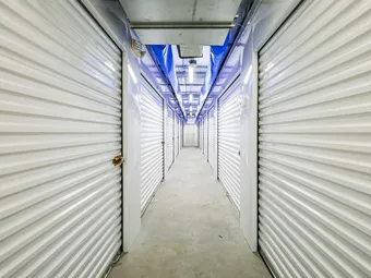 Interior hallway of storage units with overhead lights.