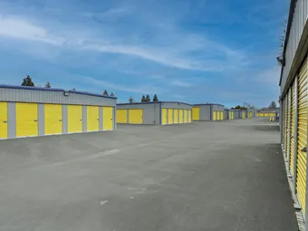 Rows of outdoor storage units with yellow doors under a blue sky.
