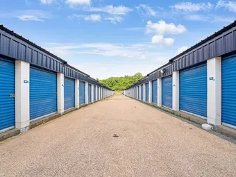 Outdoor drive-up storage units in Providence at 550 Veazie St, with blue roll-up doors and white columns lining a paved driveway