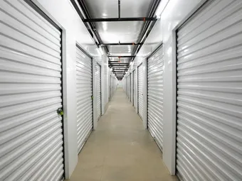Indoor climate-controlled storage in Augusta, GA, with white corrugated metal unit doors and overhead sprinkler pipes