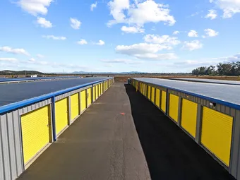 Outdoor drive-up storage units with yellow doors on a clear day