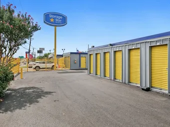 Storage facility with yellow unit doors and a blue-and-yellow pole sign.