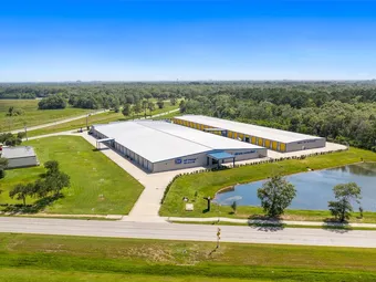 Aerial view of storage facility buildings and surrounding landscape with pond