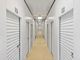 Long, brightly lit indoor storage hallway with numbered doors.