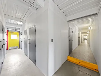 Indoor hallway with storage units and a yellow door at the end.