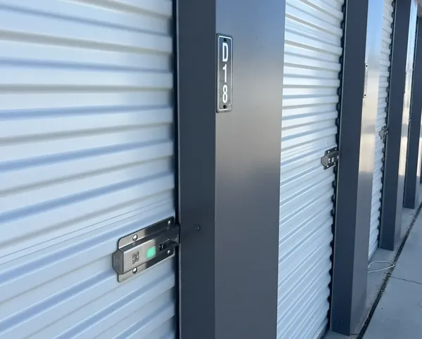 Close up of white corrugated roll-up storage doors with metal latches and unit number signage