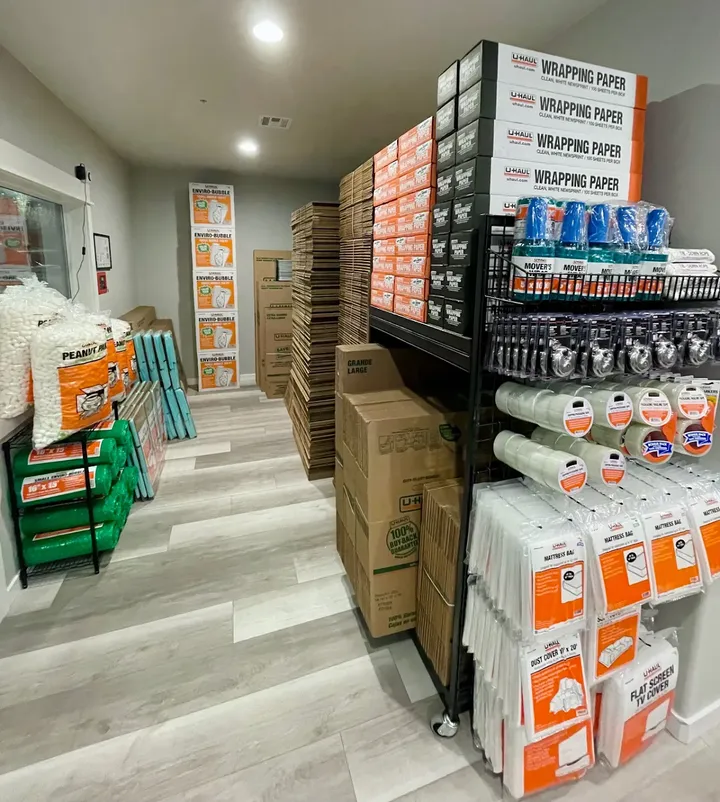 Retail office displays featuring U-Haul moving supplies, cardboard boxes, packing tape, and mattress bags for sale