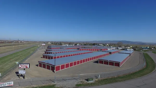 Aerial view of several long self-storage buildings with red roll-up doors and a Backyard Storage sign