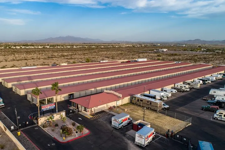 Aerial view of a self-storage facility with long red-roofed buildings, a rental office, and RV parking