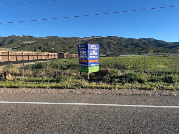 Purely Storage Parowan signage stands by a road near storage units with a mountain backdrop