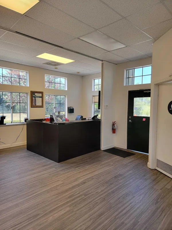 A storage facility leasing office featuring a dark reception desk, wood-look flooring, and large windows